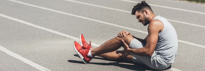 A man holding his leg in pain.