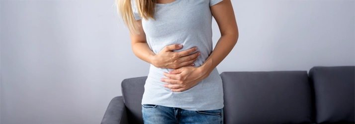 Chiropractic Waukee IA Pelvic Floor Dysfunction A woman holding her stomach in pain.